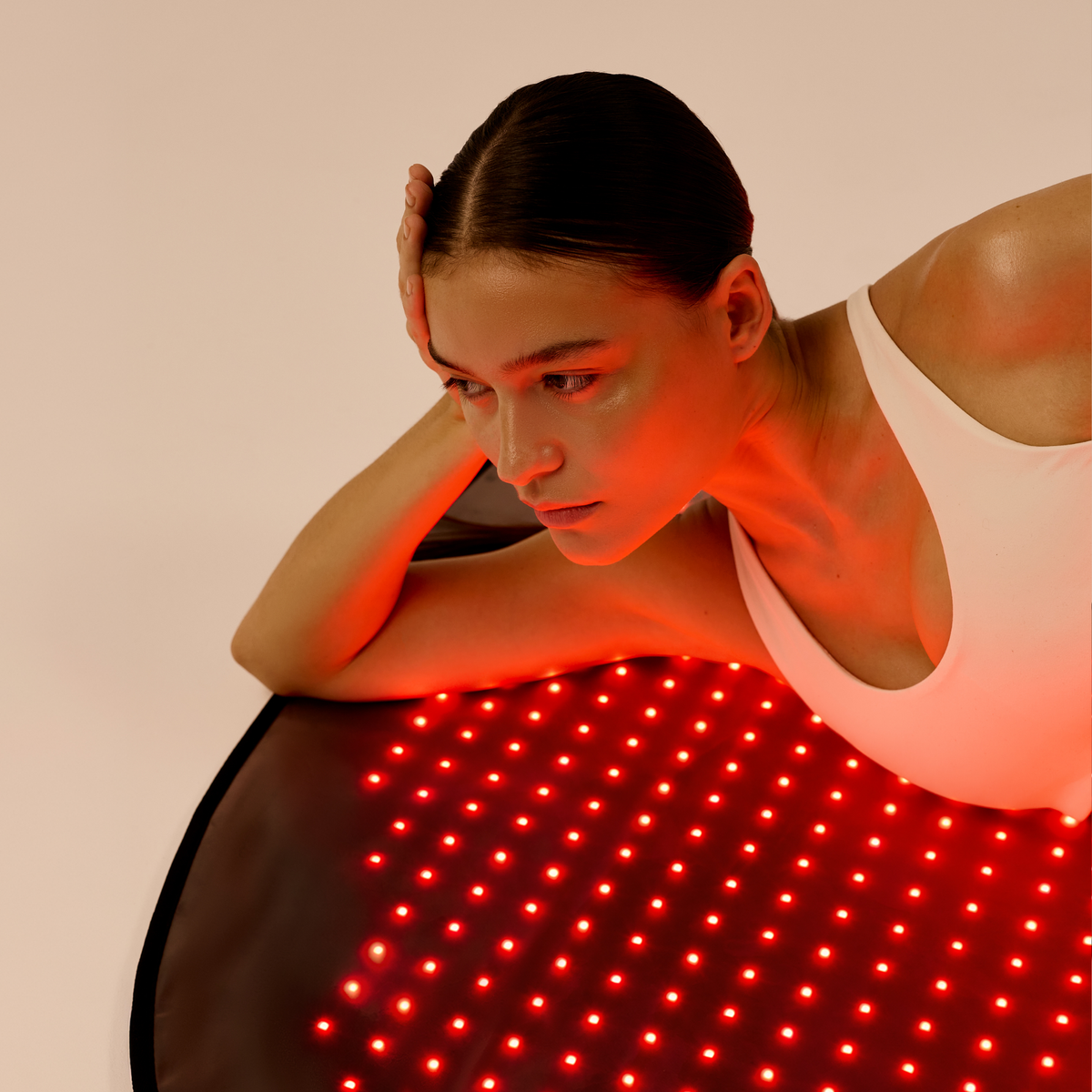 Donna sul tappetino LED Restora acceso sostiene il busto con le braccia